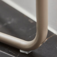 Beige furniture leg against a dark marble surface, showcasing subtle texture and smooth curves.
