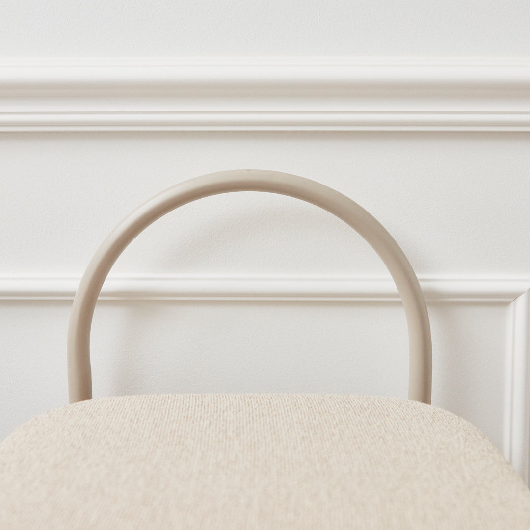 Beige textured chair with a smooth, curved beige handle against a white background. Subtle and modern design.