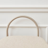 Beige textured chair with a smooth, curved beige handle against a white background. Subtle and modern design.