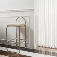Beige upholstered stool with a sleek metal frame, featuring clean lines and a modern design against a neutral backdrop.
