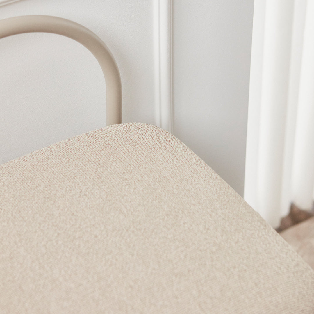 Beige textured chair cushion with subtle patterns, complemented by a soft, neutral-toned metal frame.