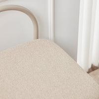 Beige textured chair cushion with subtle patterns, complemented by a soft, neutral-toned metal frame.