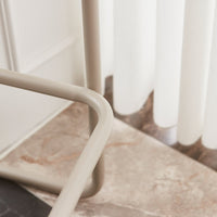 Beige metal frame against a marble surface, with soft white vertical blinds in the background.