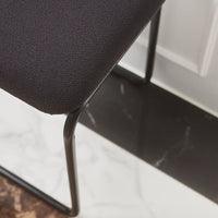 Black textured chair fabric with a sleek metal frame, set against a marble and dark patterned floor.
