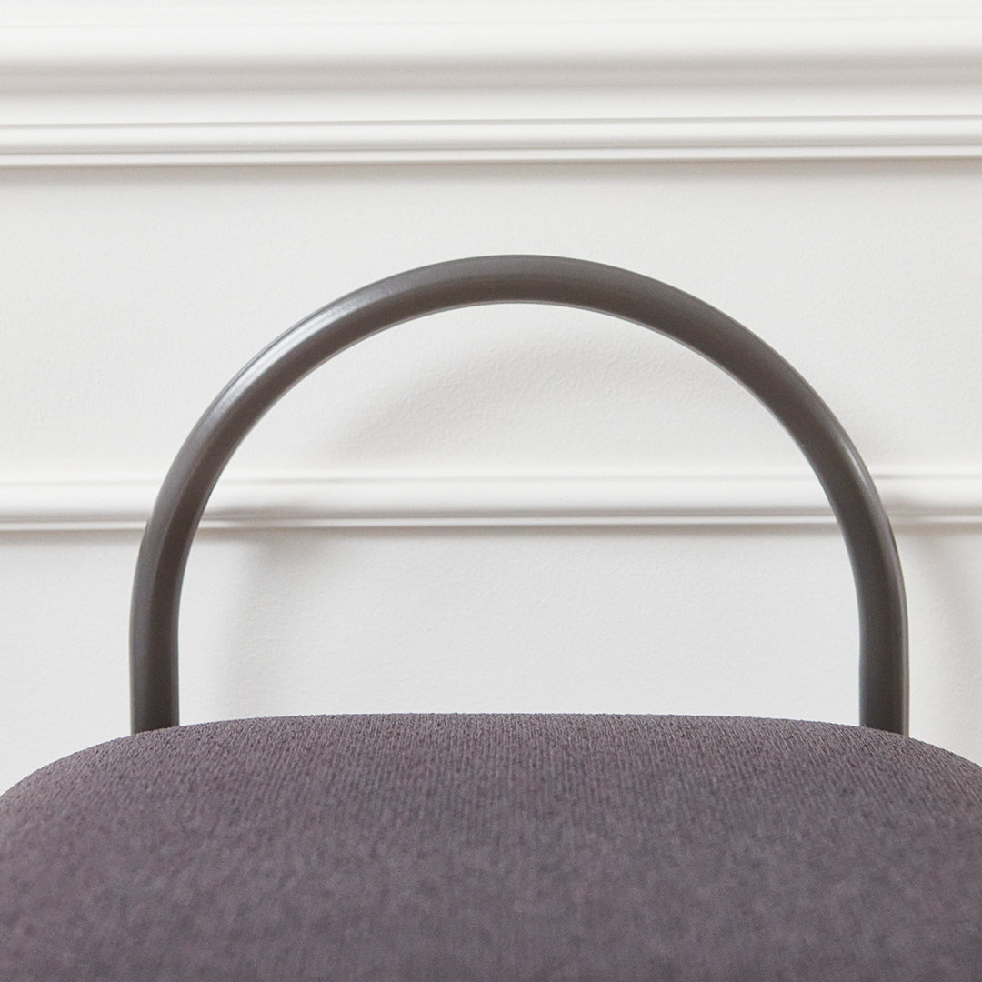 Gray upholstered chair with a sleek dark metal frame and smooth curved backrest, set against a white backdrop.