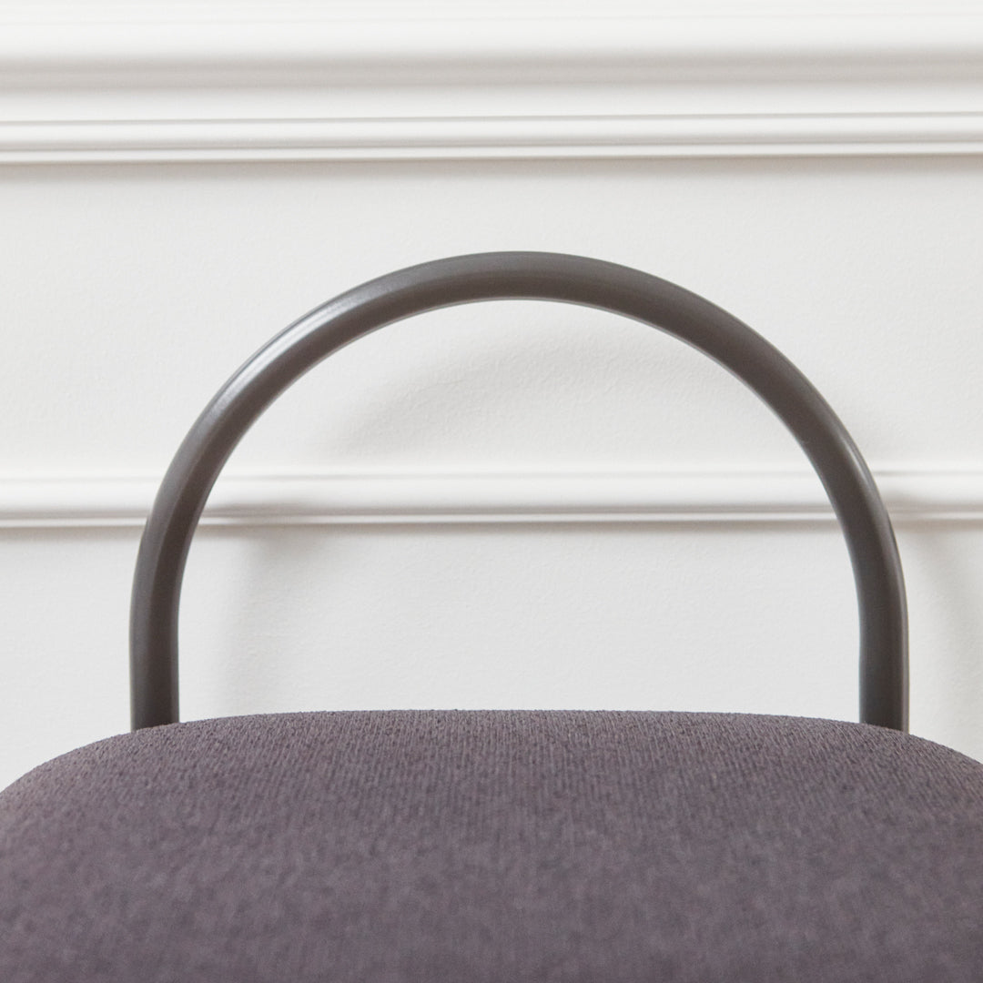 Gray upholstered chair with a sleek, curved black metal frame against a white wall.