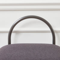 Gray upholstered chair with a sleek, curved black metal frame against a white wall.