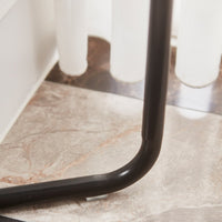 Black metal leg with a smooth curve on a stylish marble floor. Minimalist design complements modern interiors.