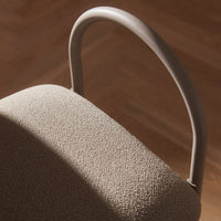 Beige textured fabric with a curved grey handle against a warm wood background. Elegant and modern design.