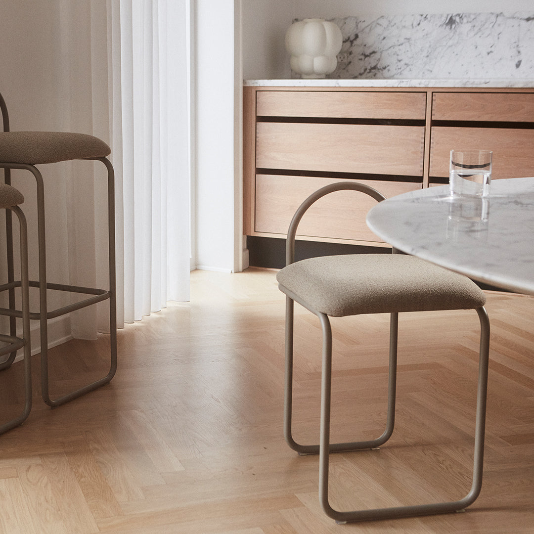 Neutral beige seat cushions on minimalist gray metal frames, paired with warm wood tones and a marble table surface.