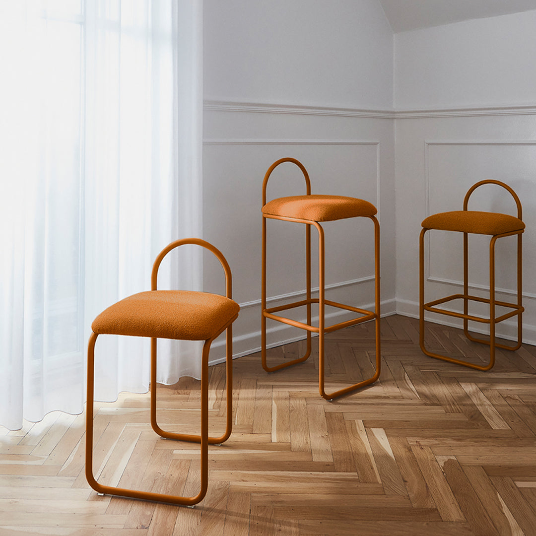 Set of three modern orange bar stools with sleek metal frames, featuring a minimalist design and soft, textured upholstery.