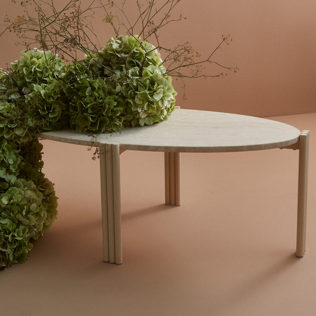 Light wood table with a smooth finish, complemented by vibrant green floral accents against a peach background.