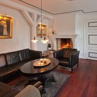 Elegant black leather sofas, dark wood table, intricate blue area rug, and warm brown hardwood flooring.