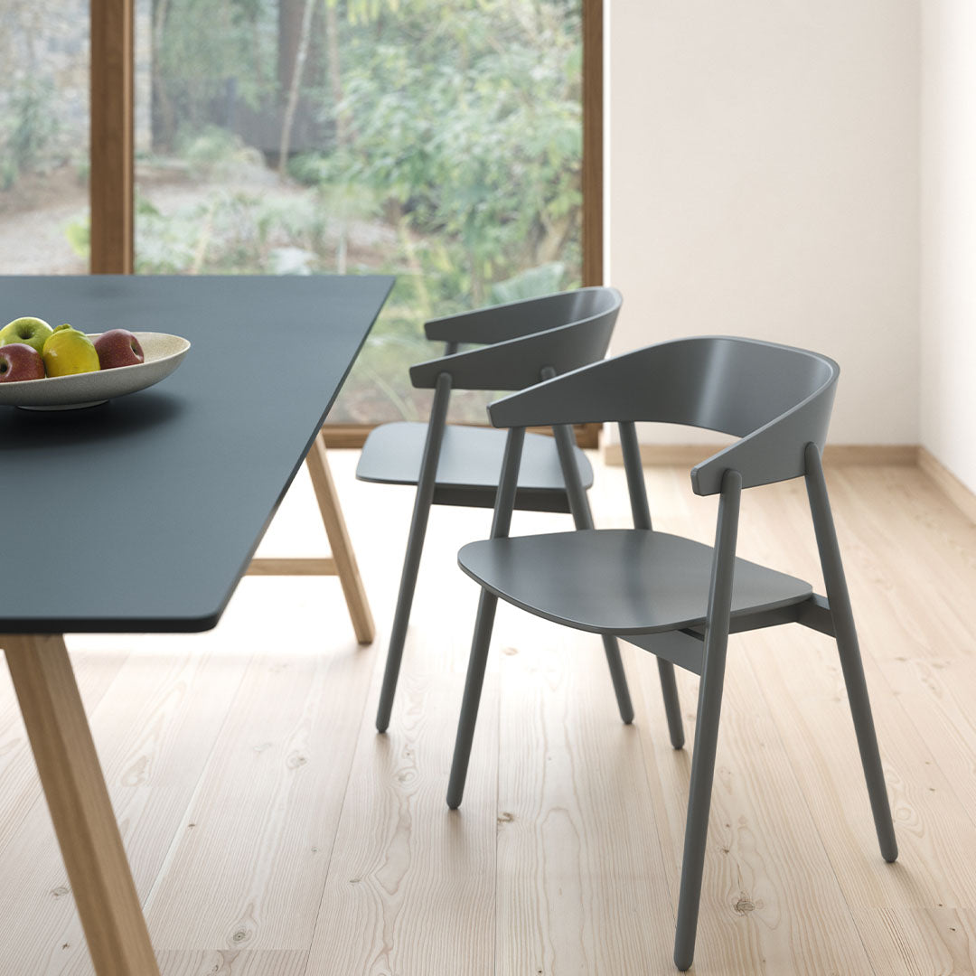Gray modern chairs paired with a sleek black table in a bright, minimalist interior with wooden floors.