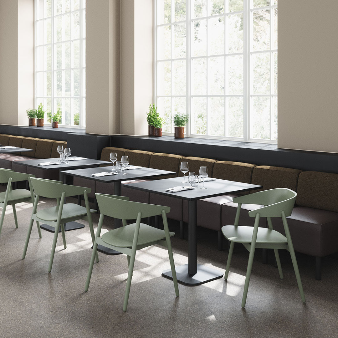 Modern dining set with mint green chairs, dark tabletops, and brown upholstered benches against soft beige walls.