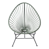 Green Acapulco chair with a unique open lattice design and black metal frame, perfect for modern outdoor decor.