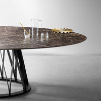 Oval dark marble table with subtle white veining, featuring a sleek black geometric base. Modern and elegant design.