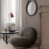 Curved green chair in a modern room, featuring neutral tones and soft textures, complemented by a sleek black table.