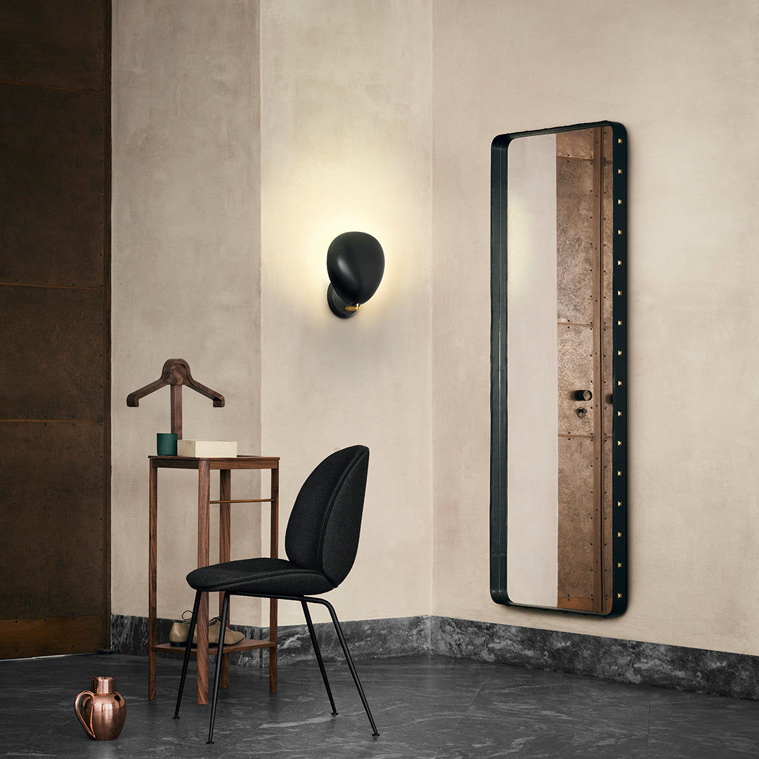 Full-length mirror with a sleek black frame and striped beige and brown design, set against a neutral wall.