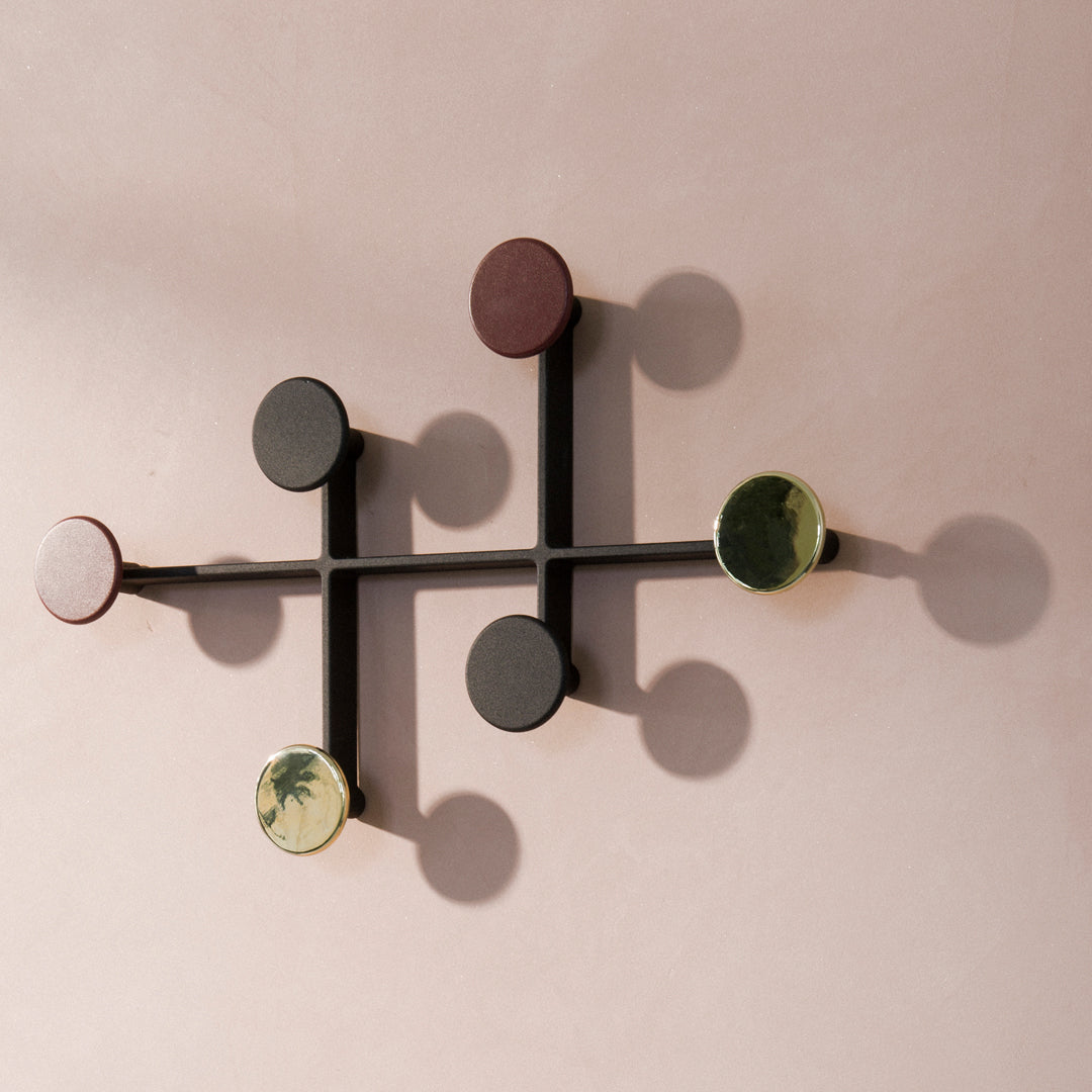 Colorful wall hooks in burgundy, green, black, and earthy tones with a modern geometric pattern.