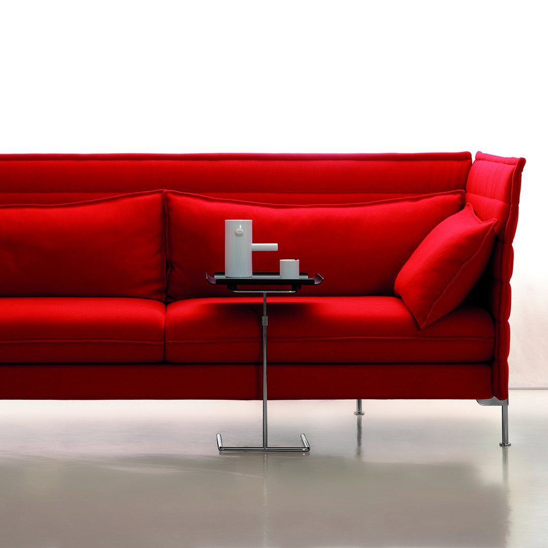 Bright red sofa with plush cushions, featuring a sleek modern design and a minimalist table in a neutral setting.