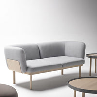 Modern gray fabric sofa with smooth curves and light wood legs, complemented by minimalist circular tables.
