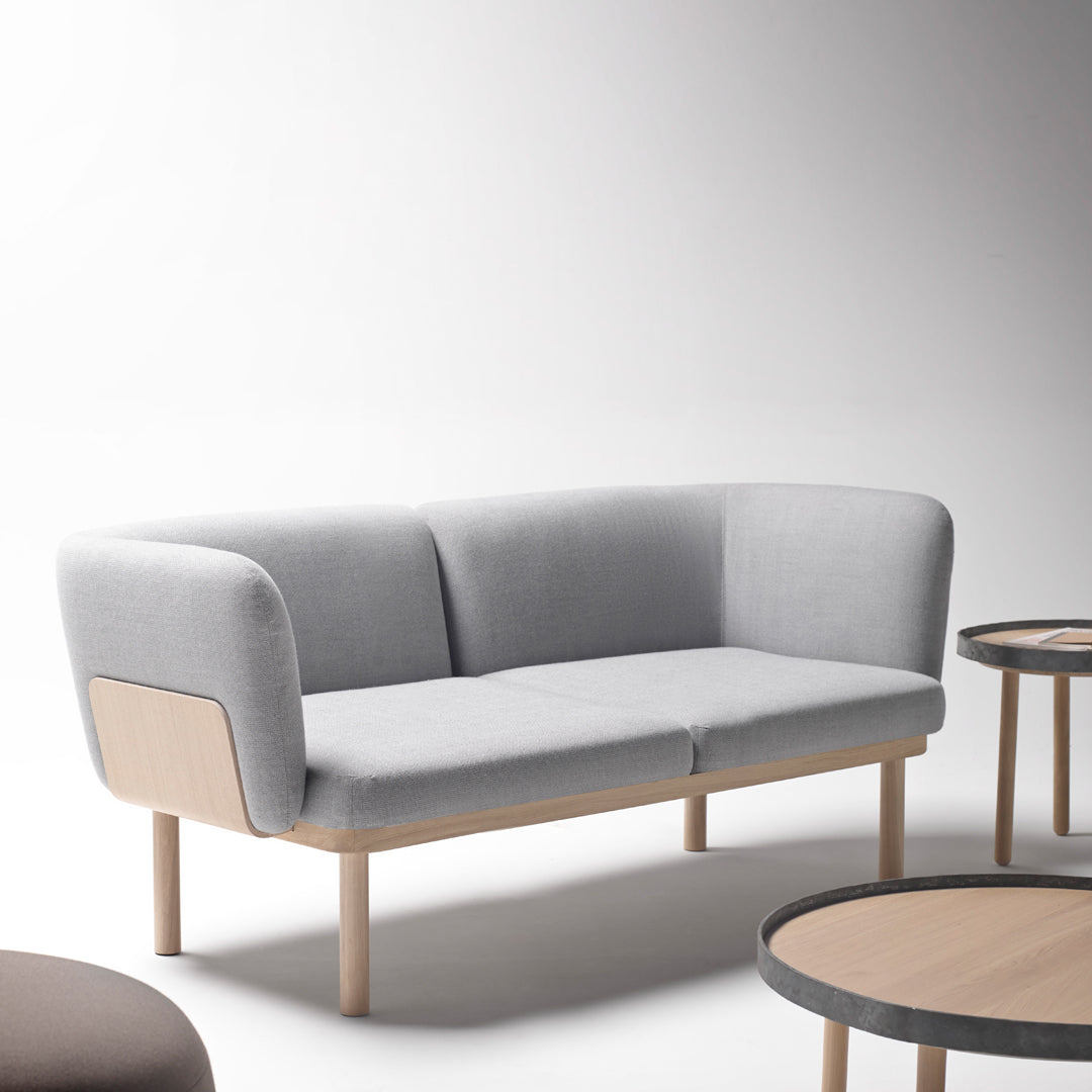 Grey upholstered sofa with curved design, featuring light wooden legs and a minimalist aesthetic.