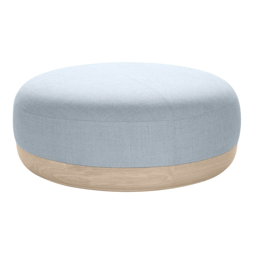 Light blue round pouf with a smooth fabric surface and a natural wood base. Minimalist design, calming colors.