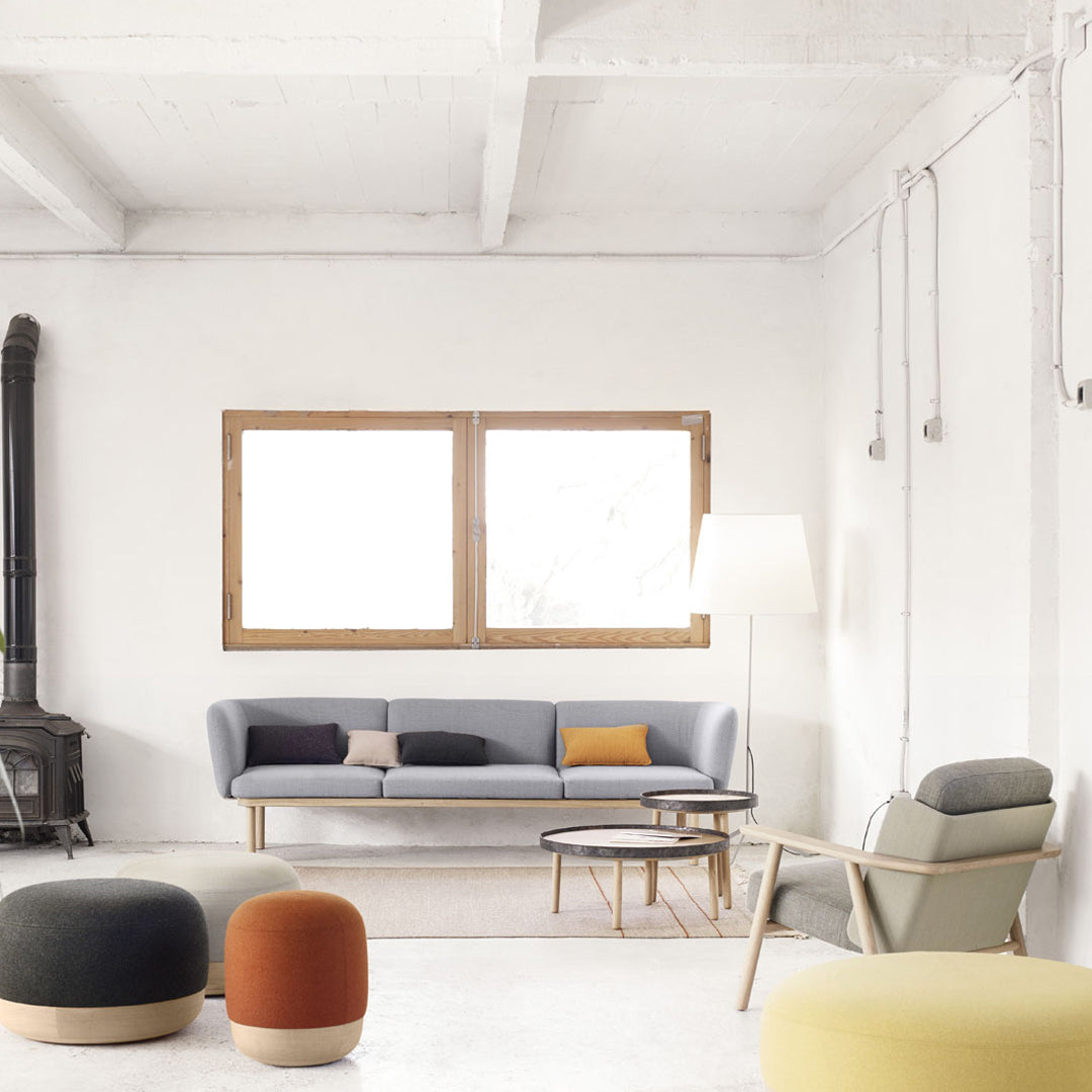 Modern living room featuring a light gray sofa, vibrant orange, yellow, and green poufs, and neutral decor.
