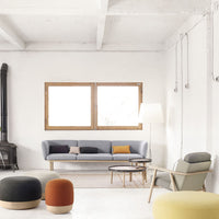 Modern living room featuring a light gray sofa, vibrant orange, yellow, and green poufs, and neutral decor.