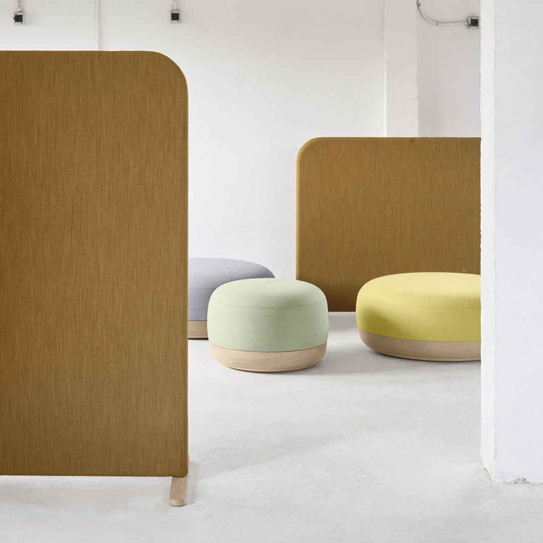 Multi-colored poufs in soft green, yellow, and gray, with warm wooden accents and a minimalist backdrop.