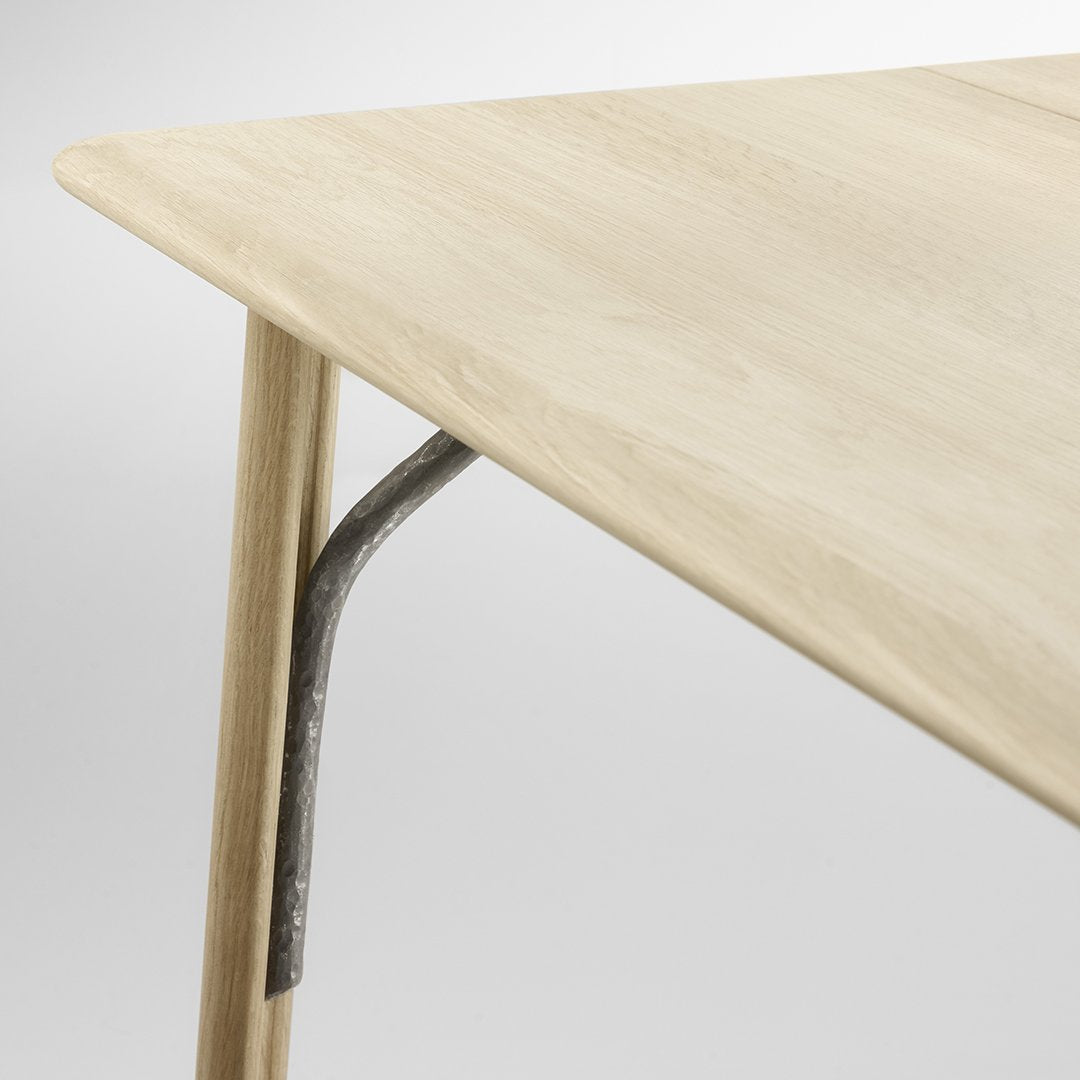 Light wood tabletop with a smooth finish and subtle natural grain, featuring a minimalist design and metallic support.
