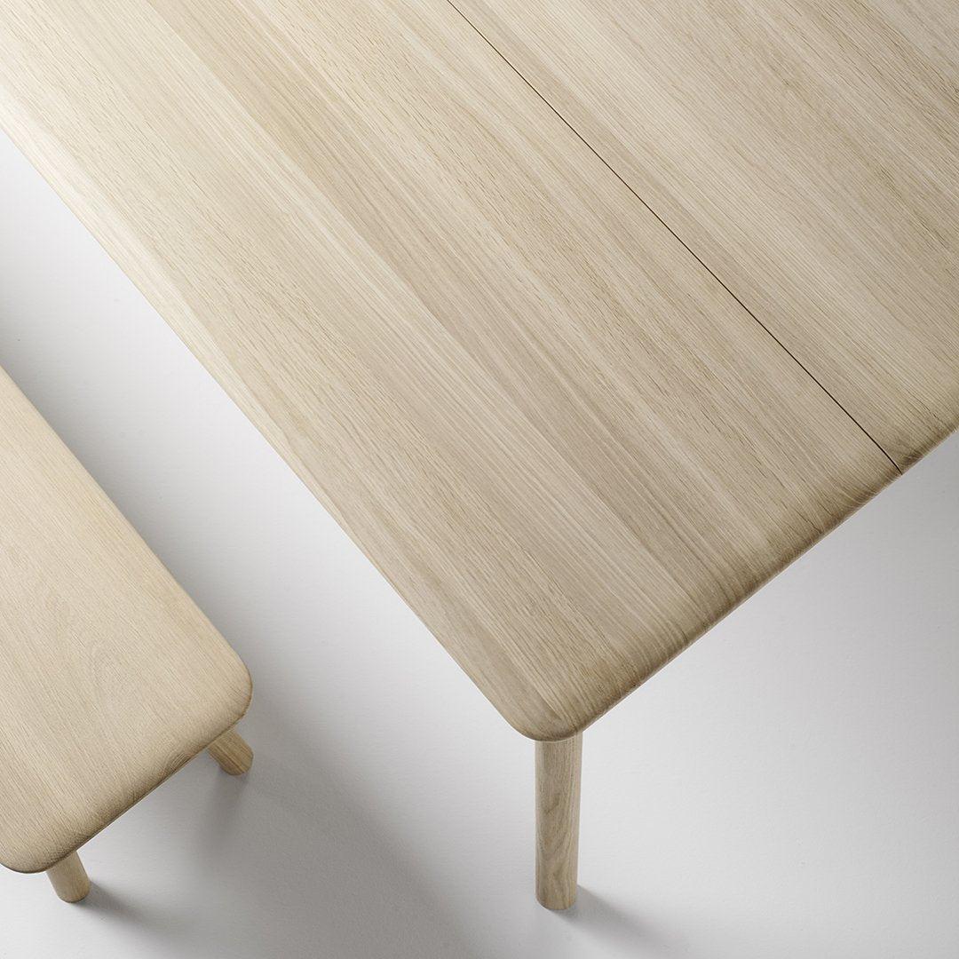Light oak wood table with a smooth, natural finish and subtle grain patterns, complemented by a matching bench.