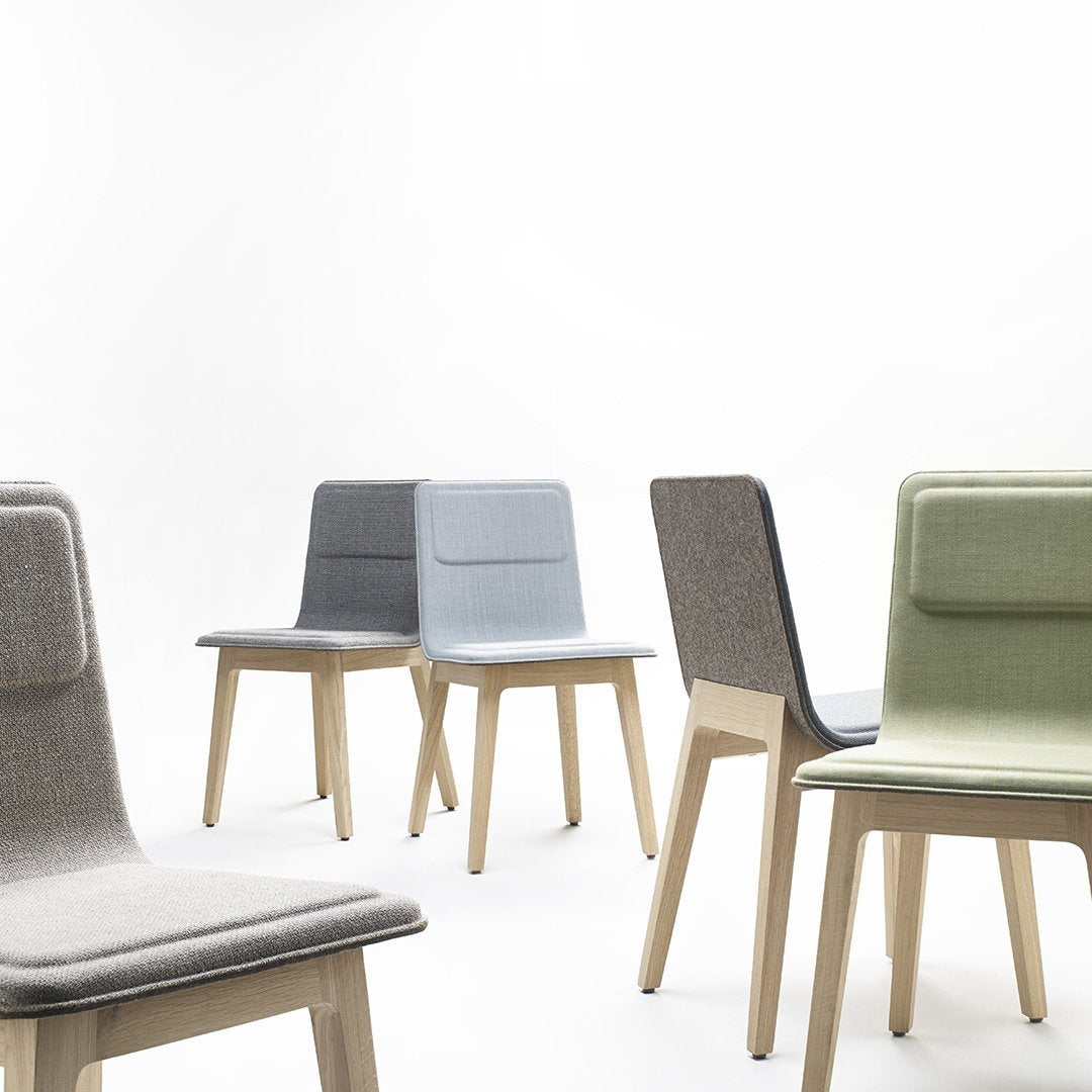 Modern chairs featuring grey, light blue, and green upholstery with textured patterns and wooden legs.