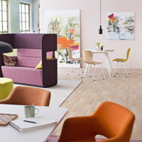 Modern interior with vibrant purple, orange, and green furniture; colorful abstract wall art; warm wood flooring.