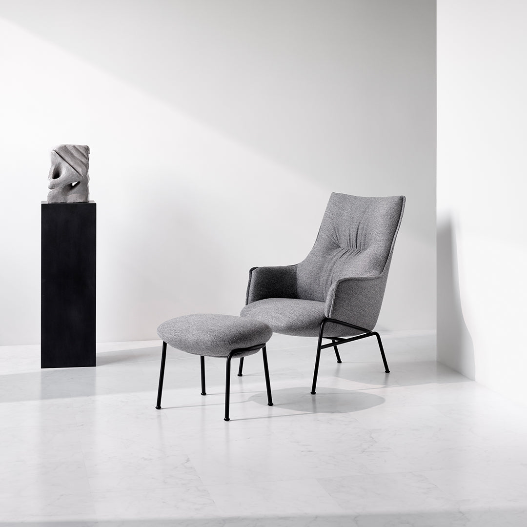 Gray upholstered chair with matching footrest, featuring clean lines and a modern minimalist design.