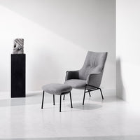 Gray upholstered chair with matching footrest, featuring clean lines and a modern minimalist design.