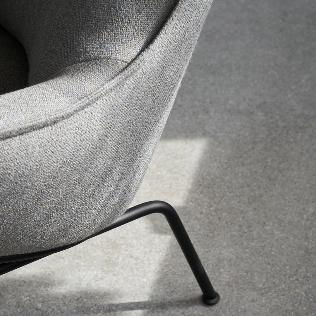Gray textured fabric armchair with sleek black metal legs, showcasing a minimalist and modern design.