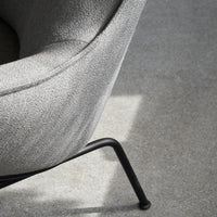 Gray textured fabric armchair with sleek black metal legs, showcasing a minimalist and modern design.