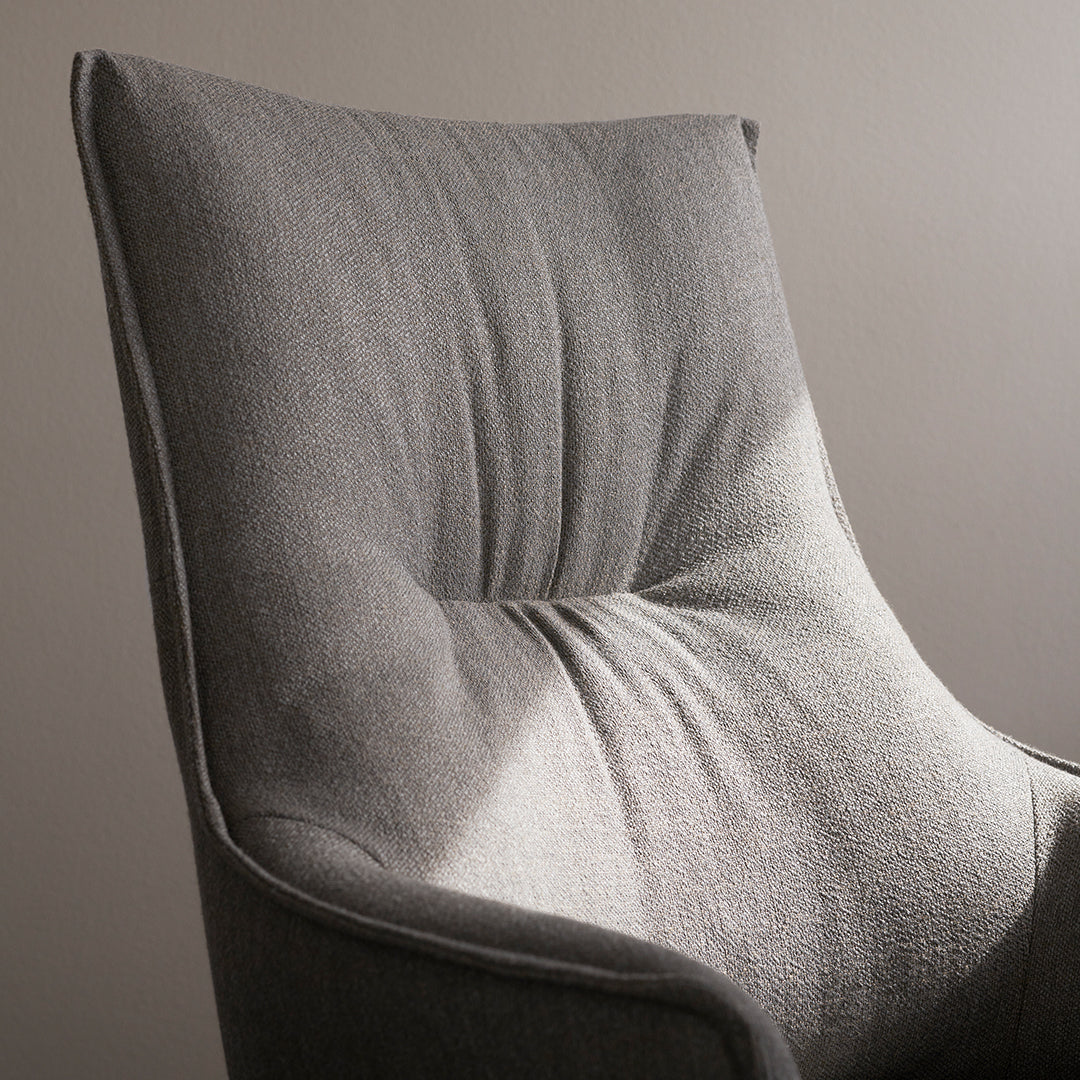 Gray upholstered chair featuring a smooth texture and subtle tufted pattern. Perfect for modern interiors.