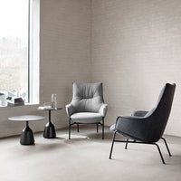 Gray upholstered armchairs with black metal legs, featuring smooth and textured patterns, set against a neutral background.