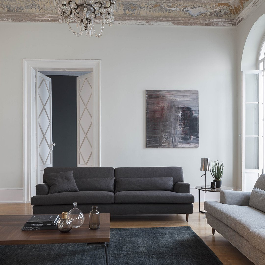 Elegant dark gray sofa with a subtle texture, set against a neutral backdrop and rich artistic wall decor.