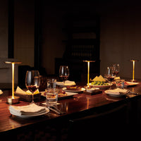 Elegant dining setting with warm golden hues, dark wood table, and vibrant green and red dishes complementing the ambiance.
