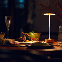 Elegant gold lamp with warm light, set against earthy tones of a wooden table and vibrant green salad.