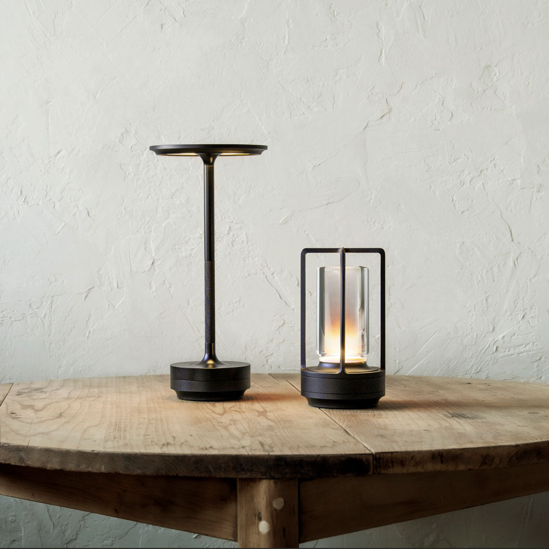 Stylish black table lamps with gold accents, sleek lines, and glass shades on a rustic wooden surface.
