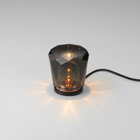 Stylish black crystal lamp with geometric pattern, warm golden light reflections, and subtle sparkling accents.