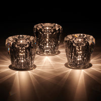 Set of three crystal candle holders, featuring clear glass with shimmering starburst patterns and soft, radiant highlights.