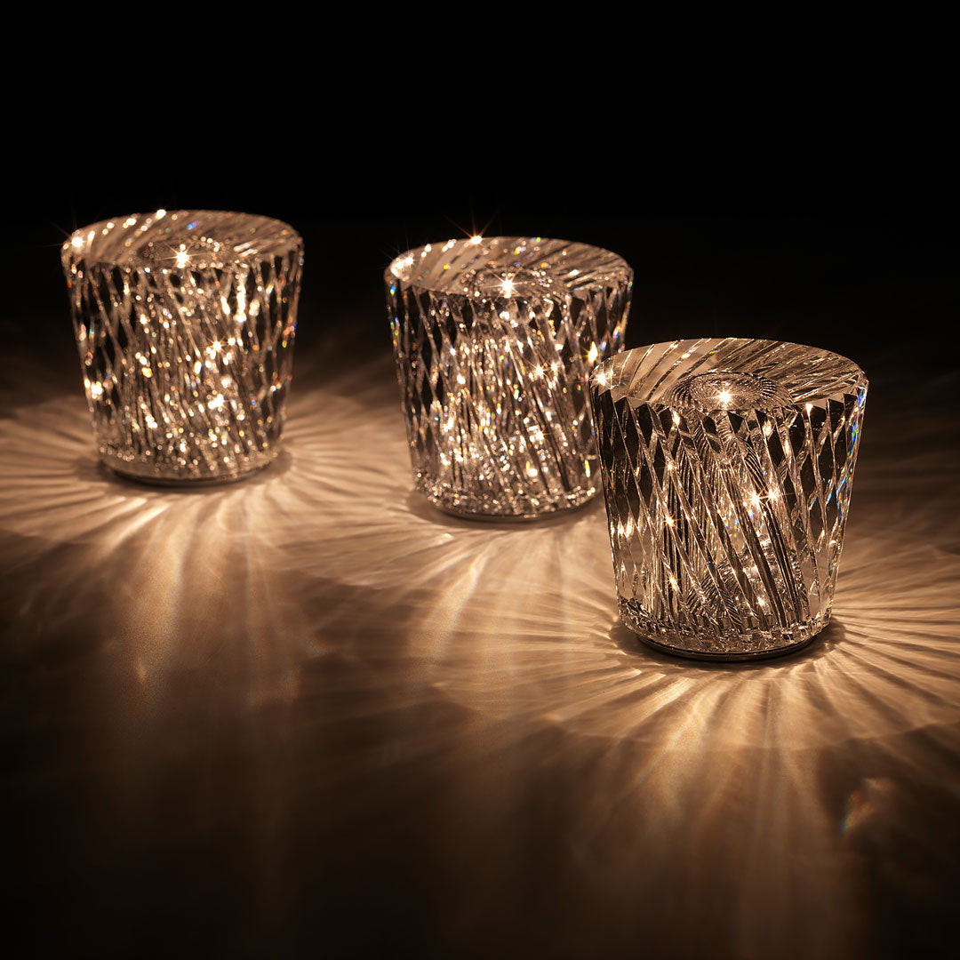 Set of three crystal candle holders with reflective surfaces, featuring intricate cut patterns and sparkling light reflections.