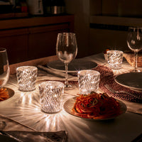 Twinkling crystal candle holders with intricate patterns, reflecting warm white light on a stylish dining table setting.