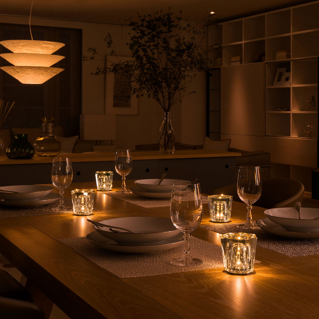 Warm golden tones illuminate a modern dining table, featuring elegant glassware and soft, textured patterns.